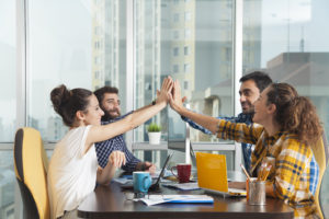 Four business colleagues giving high-five at office